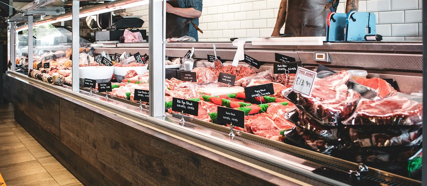 Butcher and deli counter with weighed meat products and shelf-edge price labels, a typical setting for scale-integrated EPOS